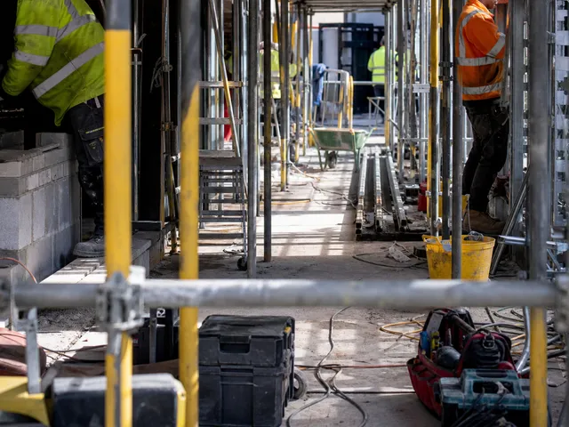 Baustelle mit mehreren Gewerken und Material als Symbol für parallele Arbeiten und Abstimmungsbedarf