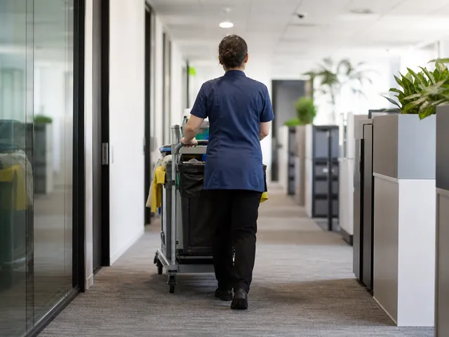 Reinigungskraft mit Wagen im Flur als Symbol für Personalfluktuation bei der Gebäudereinigung
