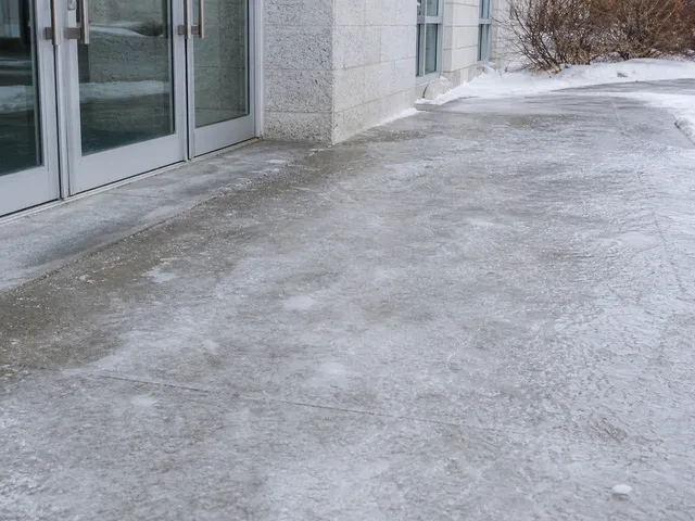 Glatter, vereister Gehweg vor einem Gebäudeeingang als Symbol für Haftung bei Stürzen im Winter